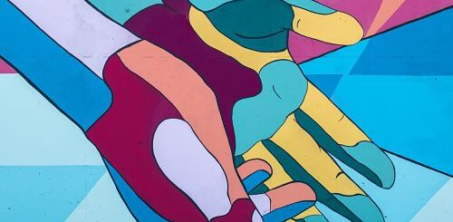 Dessin de mains tendues. Les mains sont colorées en mosaïque de couleur bleu, rose, vert, orange et bordeau