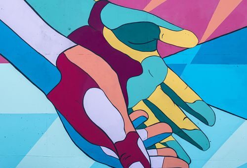 Dessin de mains tendues. Les mains sont colorées en mosaïque de couleur bleu, rose, vert, orange et bordeau
