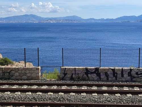 Vue sur la mer méditerranée au delà d'une voie ferrée